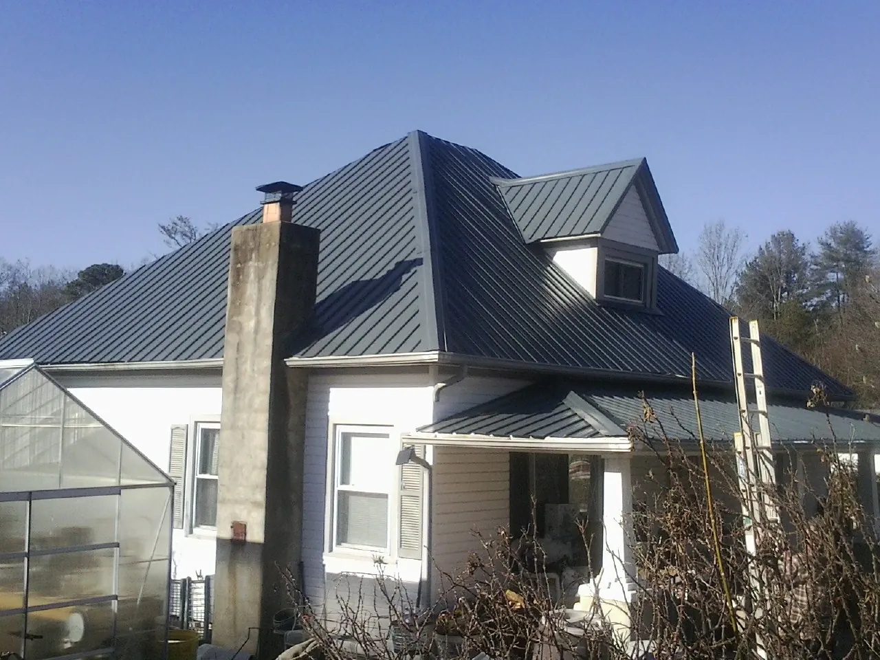 Dark blue standing seam metal roof on a white farmhouse with dormer — Slate & Tile Roof Repair by Roofing Brothers in Somis