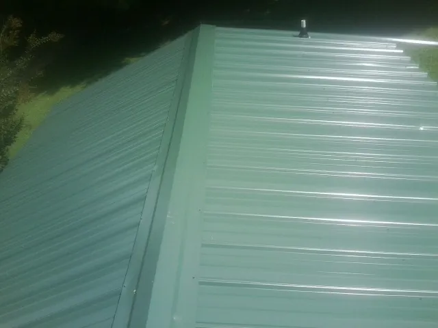 New green metal panels meeting at the ridge of a roof — Flat Roof Repair work by our crew in Somis