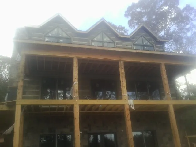 Dormers and porch framing on a large log home under construction — Roof Coating work by our crew in Somis