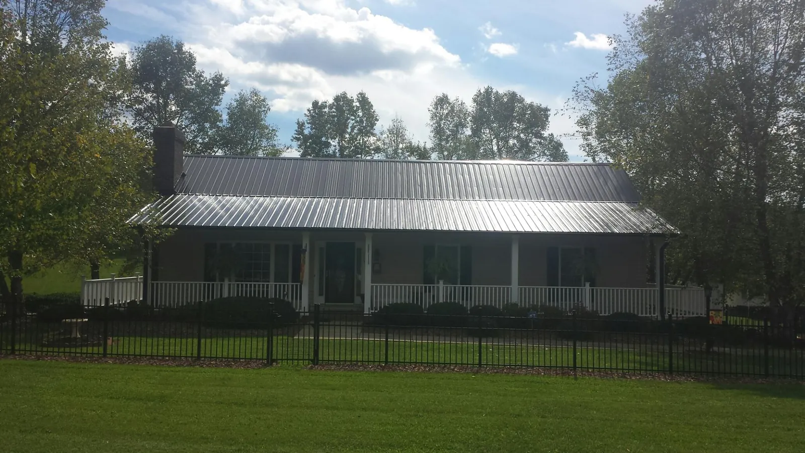 Gray metal roof on a brick ranch with a full width front porch — Gutter Guard Installation work by our crew in Somis