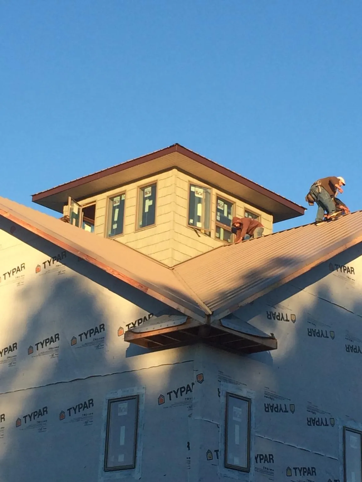 Roofers working around a rooftop cupola on a new metal roof at sunset — Roof Waterproofing in Somis by Roofing Brothers